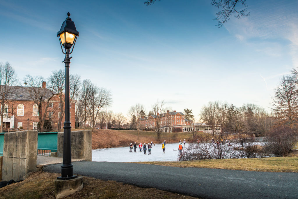 A group of students playing hockey on a pond on the Williston campus