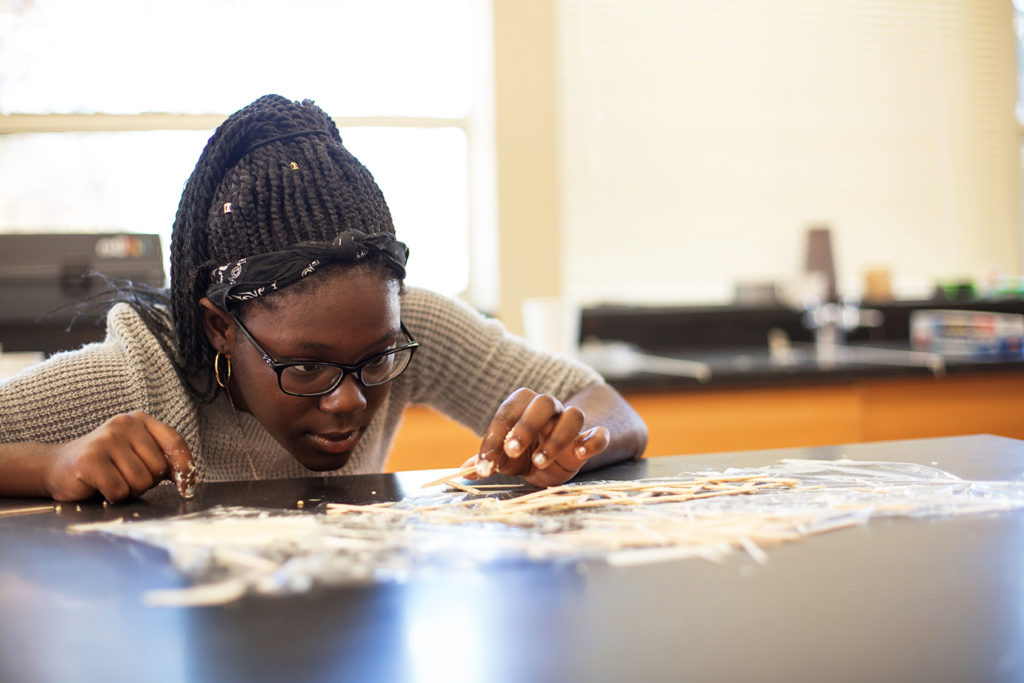 A student working intently on a project at a large table